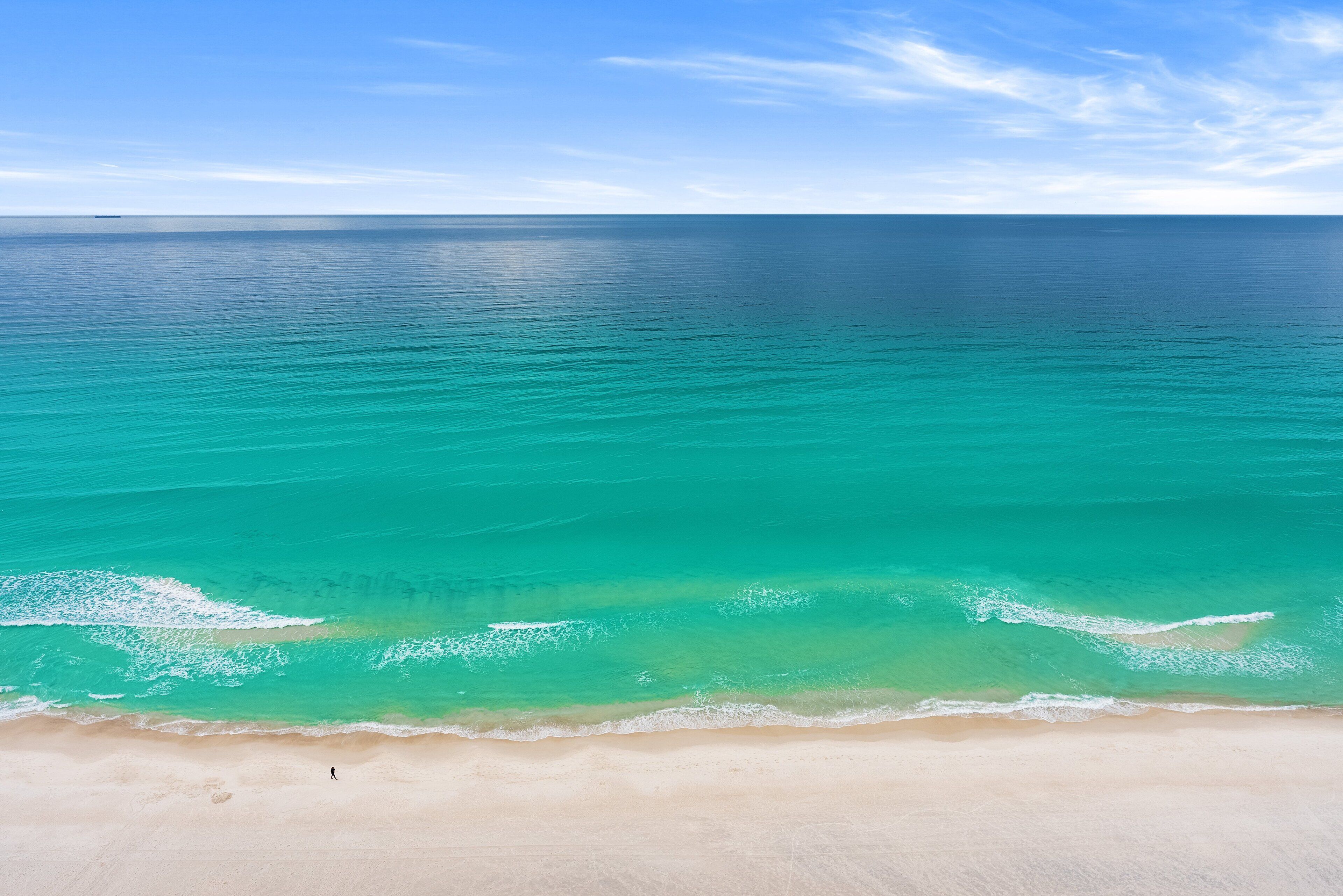 A beach with clear turquoise waters and a sandy shore.