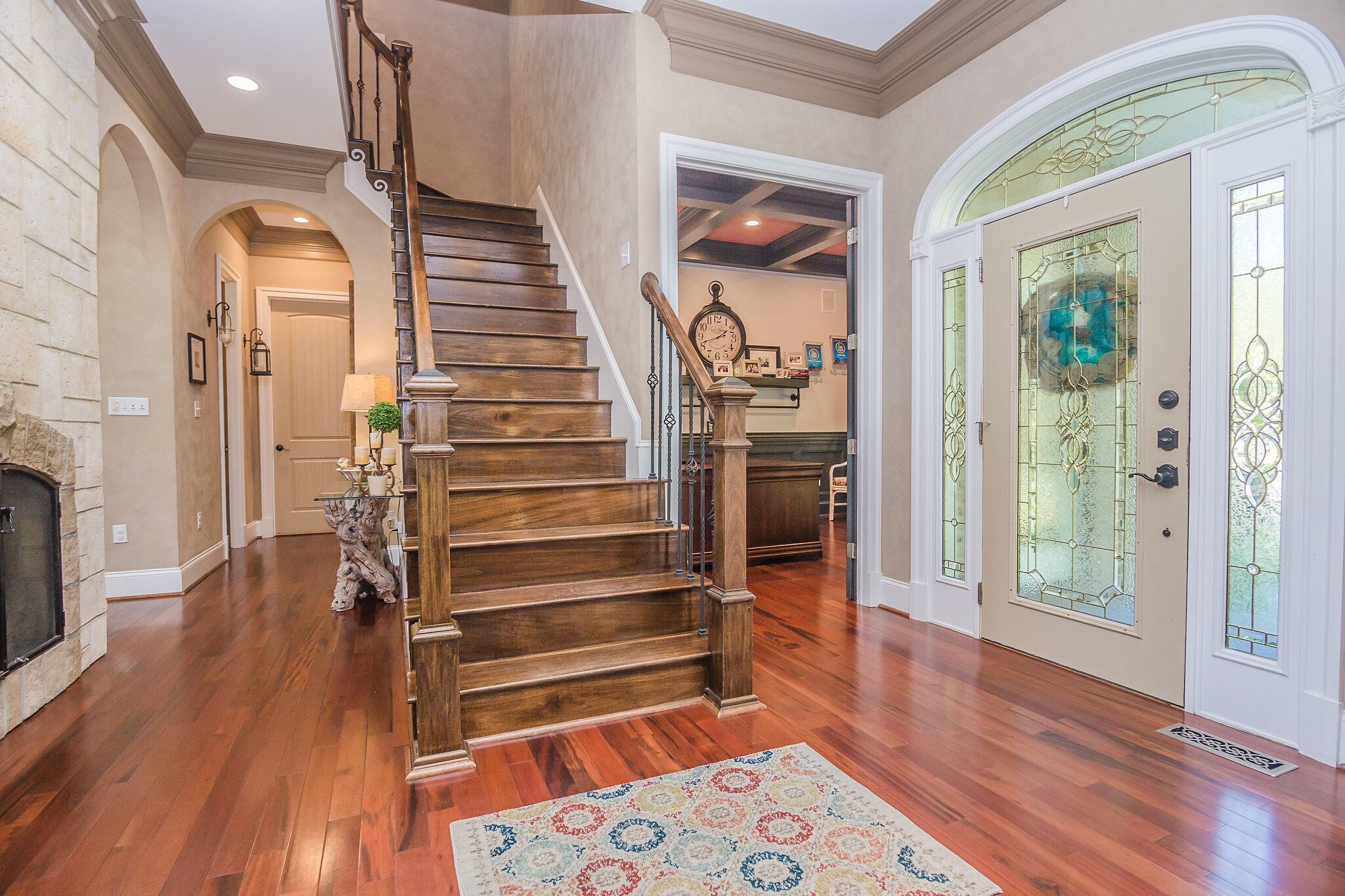 Un escalier en bois menant à un deuxième étage, une cheminée et un tapis décoratif.