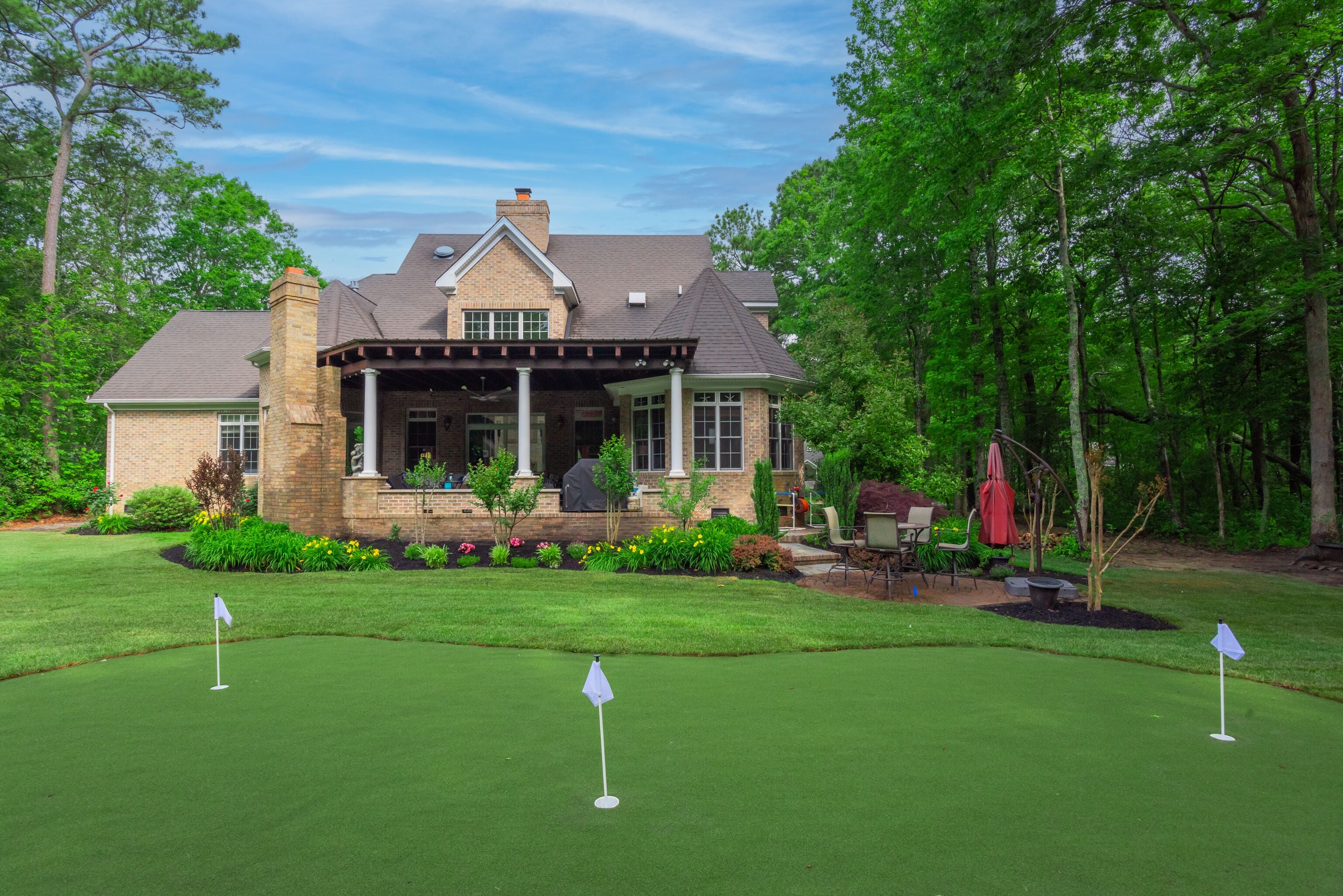 Een huis met een veranda, een gazon en een golfbaan.