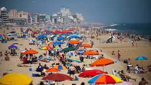 Ein überfüllter Strand mit vielen bunten Sonnenschirmen und Badegästen.