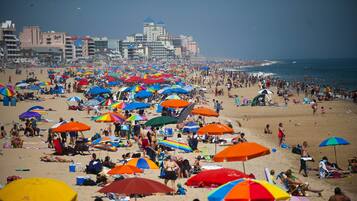 Une plage bondée, avec de nombreux parasols colorés et de nombreux vacanciers.