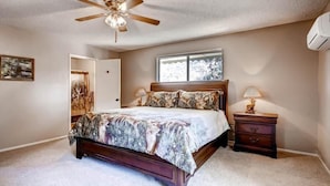 A bedroom with a bed, a ceiling fan, a nightstand, and a window. - Lazy Bear Lodge (Oakhurst)