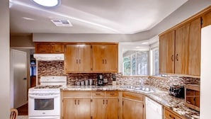 A modern kitchen with wooden cabinets, a white stove, and a granite countertop. - Lazy Bear Lodge (Oakhurst)