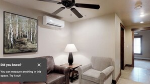 A living room with a ceiling fan, a painting, a lamp, and a sofa.