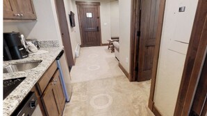 A narrow kitchen with granite countertops, a coffee maker, and a stove.