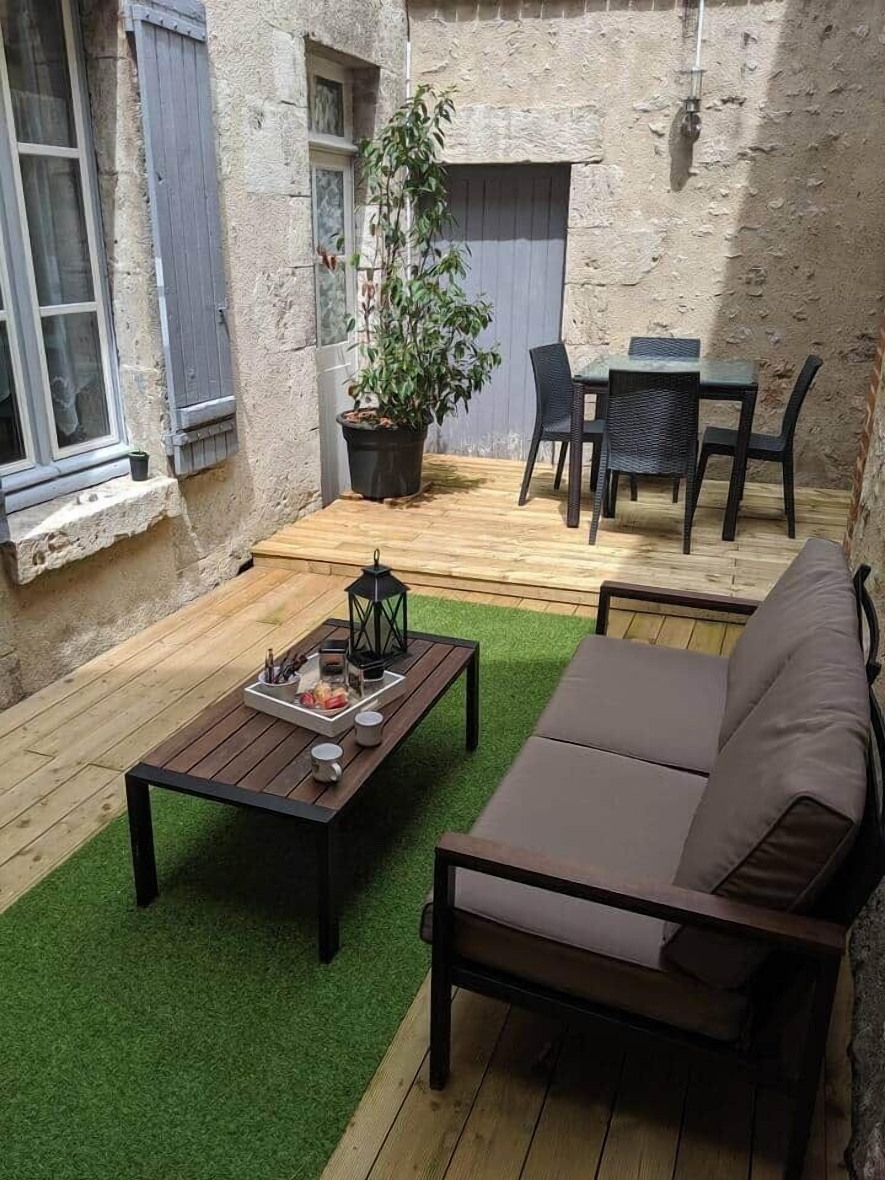 Ein gemütlicher Außenbereich mit Holztisch, einer Couch und einem Blumentopf.