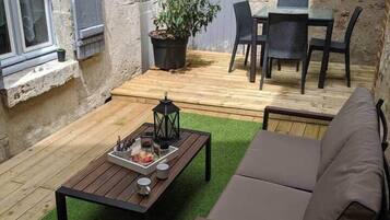 Ein gemütlicher Außenbereich mit Holztisch, einer Couch und einem Blumentopf.