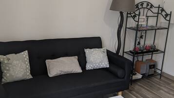 A living room with a black sofa, white coffee table, and a painting of a bridge.
