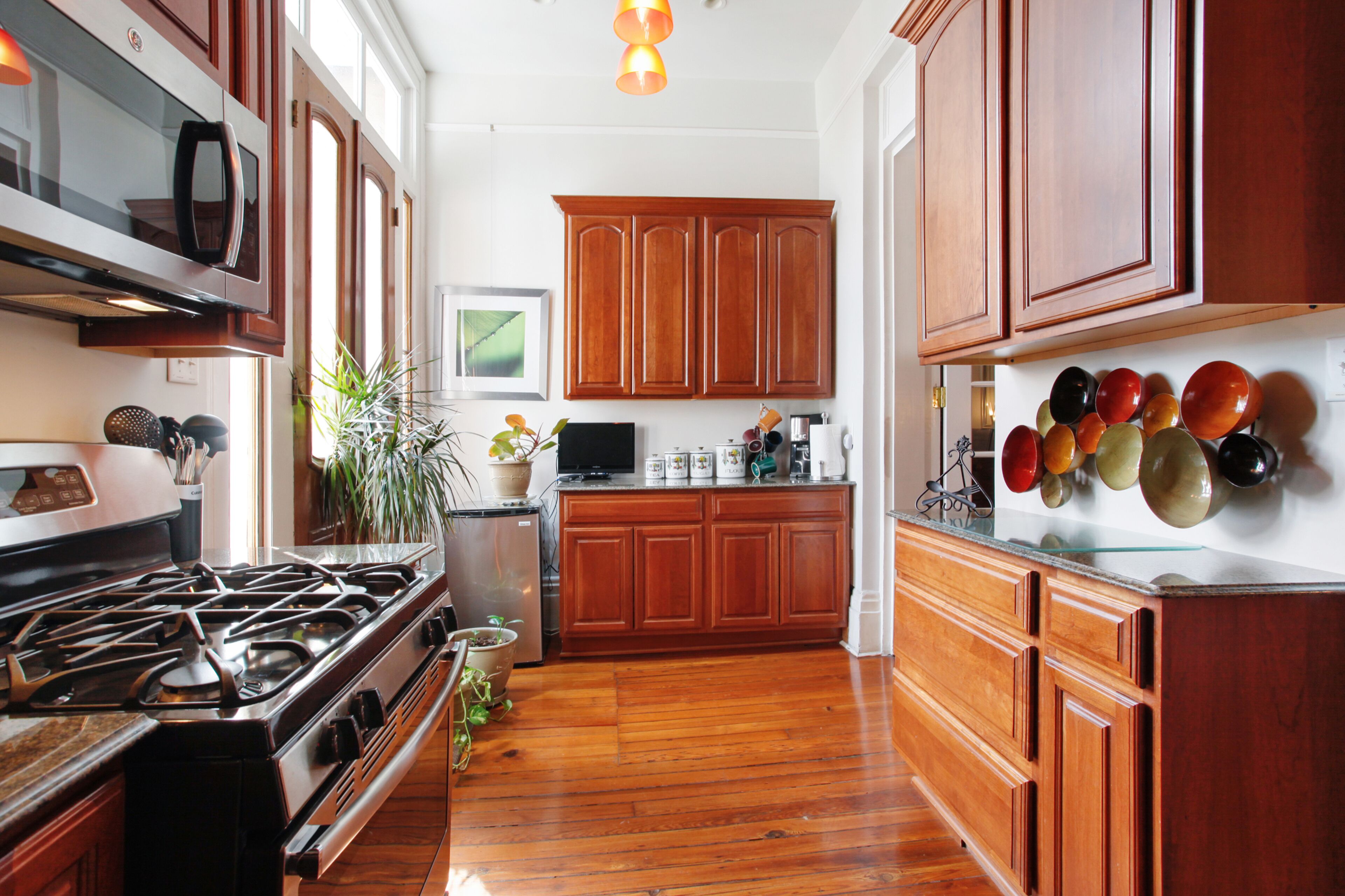 Une cuisine avec des meubles de rangement en bois, une cuisinière et un four à micro-ondes.
