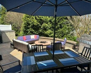 Una terrazza esterna con tavolo, sedie, divano e ombrellone.