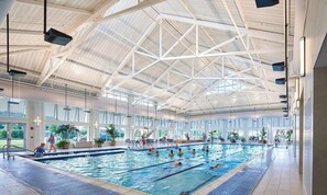 Una piscina interna con soffitto alto e ampie finestre.