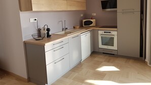 Une cuisine de taille réduite avec des meubles blancs, un four à micro-ondes, un évier et un lave-vaisselle.