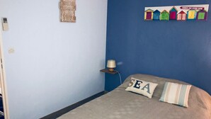 Une chambre à coucher avec un lit, une lampe fixée au mur et un panneau décoratif.