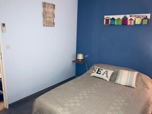 Een slaapkamer met een bed, een wandlamp en een decoratief bord.