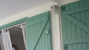 A room with a grey sofa, a teal door, and a white curtain. - Jolie CASE CREOLE, LAGON à pied, JARDIN (La Saline-Les-Bains)