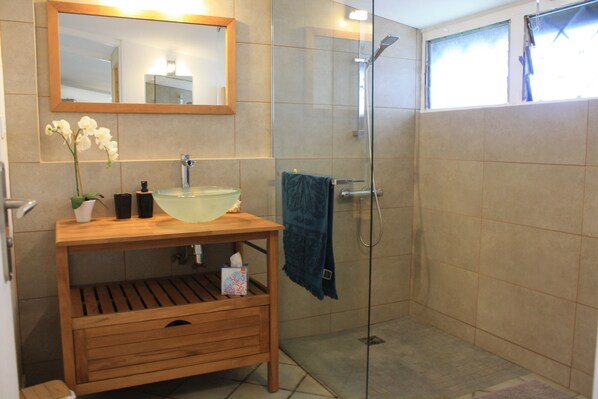 A bathroom with a wooden vanity, a glass shower enclosure, and a large mirror.