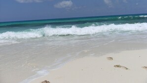 Una playa con olas y huellas en la arena.