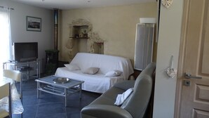 Sala de estar com sofá, televisão, mesinha e um detalhe decorativo na parede.