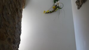 Uma escadaria com uma parede de pedra de um lado e, do outro, uma parede com uma planta pendente e uma decoração de borboleta.