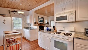 Une cuisine moderne avec des meubles blancs, une cuisinière à gaz, un four à micro-ondes et un four encastré.