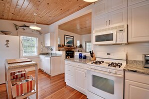 A modern kitchen with white cabinetry, a gas stove, a microwave, and a built-in oven. - Deep Water Dock & Close to Beach (Folly Beach)