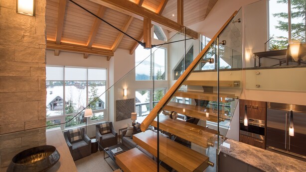 Een modern interieur met een stenen openhaard, een houten trap en een keuken met roestvrijstalen apparatuur.