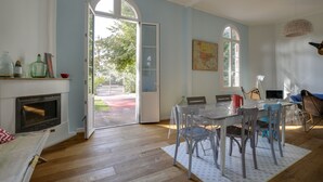 Un comedor con mesa y sillas, una chimenea y vistas al exterior a través de un ventanal abierto.