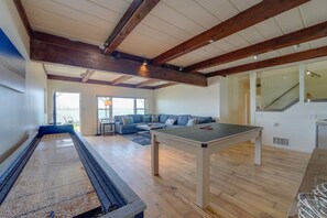 Ampla sala de estar com mesa de pingue-pongue, um sofá e vista para o exterior.