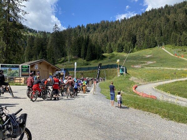 A mountain biking event with participants and spectators gathered around a gravel path.