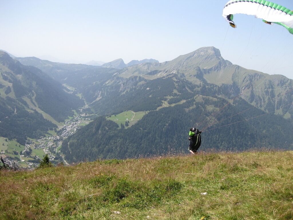A person paragliding over a mountainous landscape with a valley below.