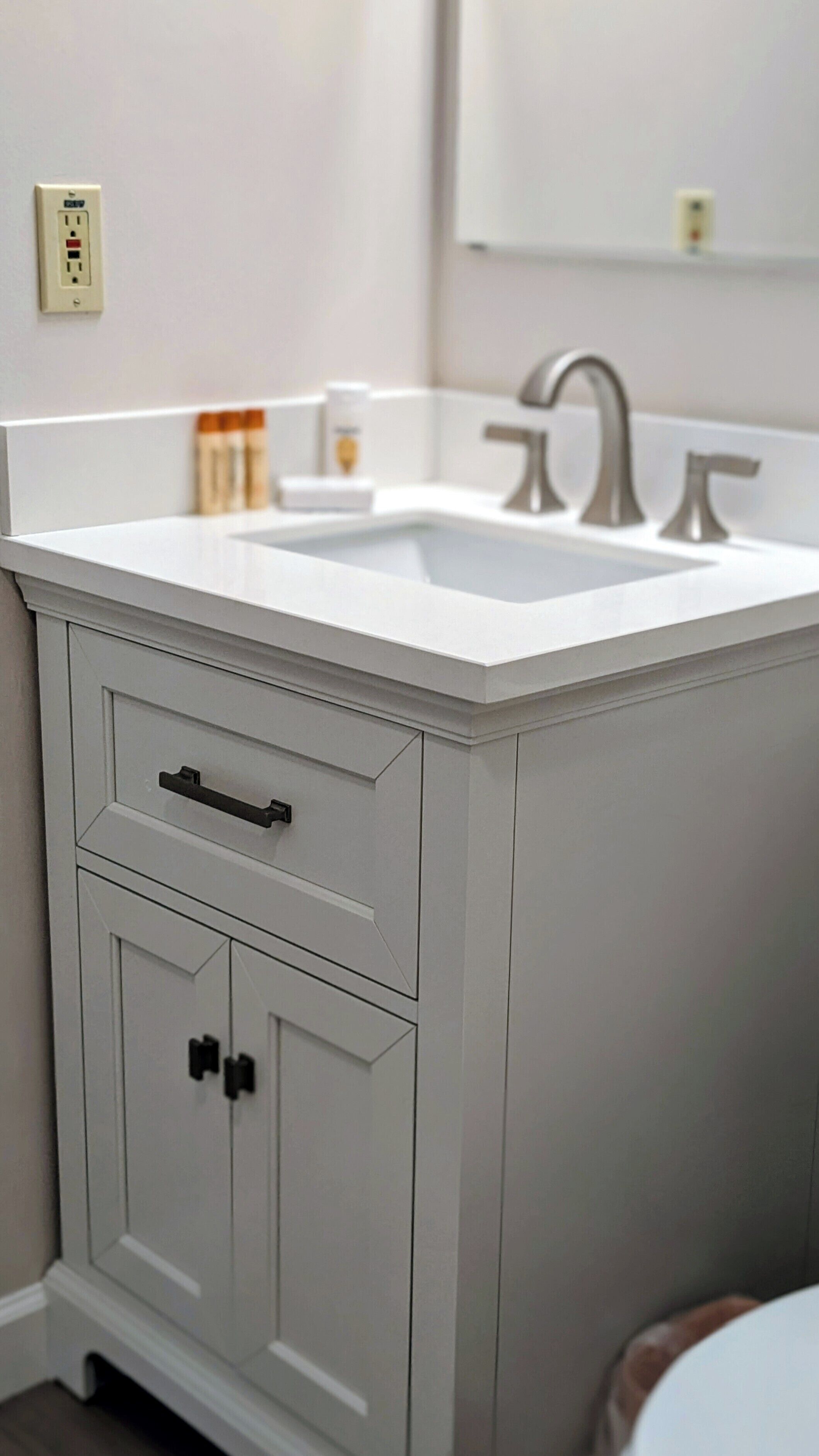 A bathroom with a white vanity, a sink, and a mirror.
