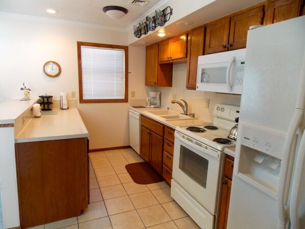 Kitchen features a sink, stove, microwave, and window with blinds.