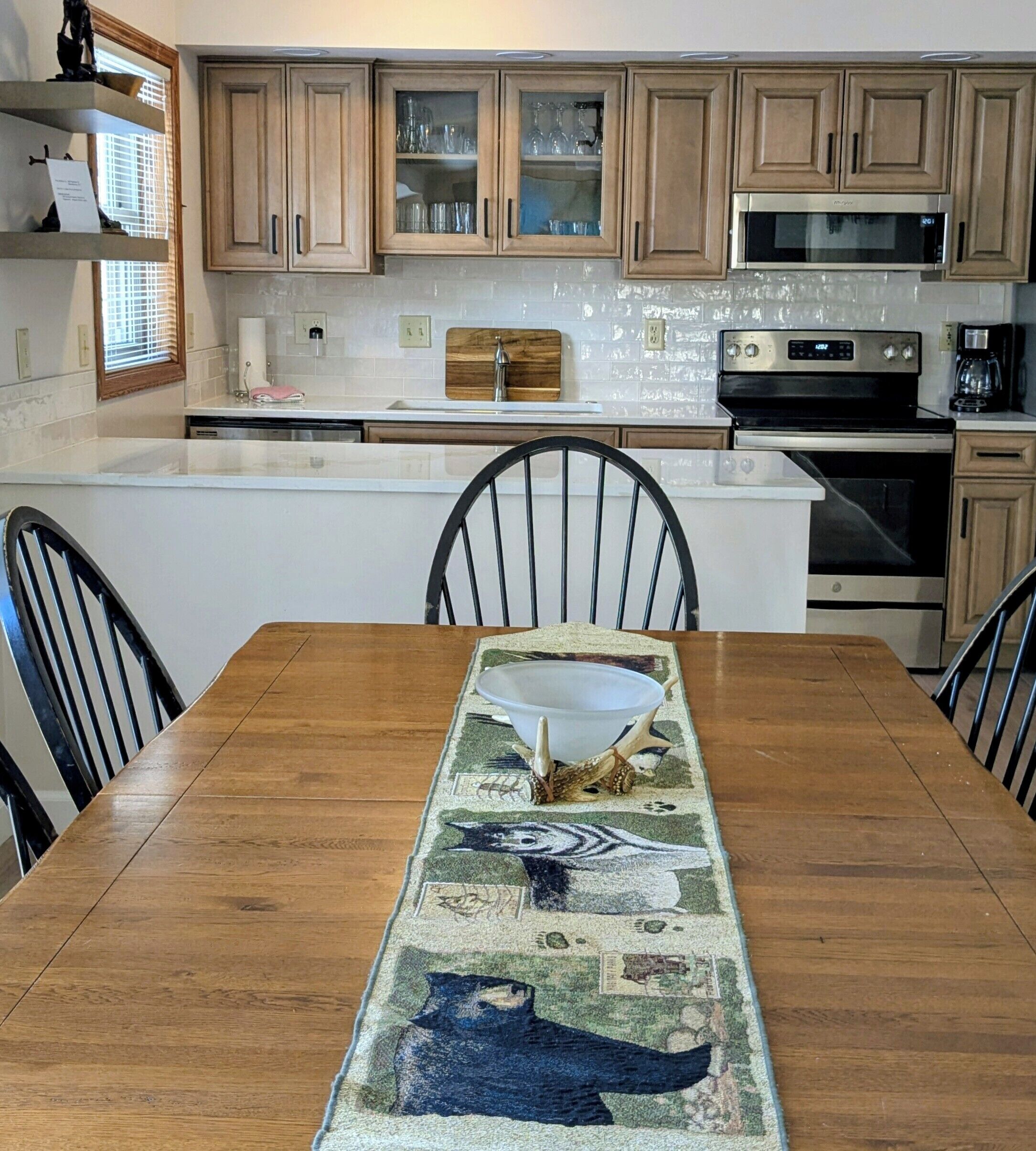 A kitchen with wooden cabinets, a microwave, an oven, and a dining table with chairs.