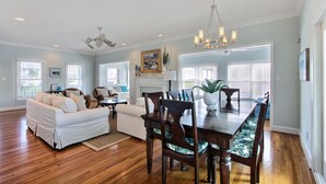 A spacious living room with a white sofa, a dining table with chairs, and a fireplace.