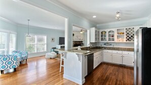 A spacious kitchen with white cabinetry, a granite countertop, and a black refrigerator.