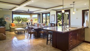 Une cuisine spacieuse dotée d’un grand îlot central, un coin repas offrant une vue agréable et un espace salon confortable avec vue sur l’extérieur.