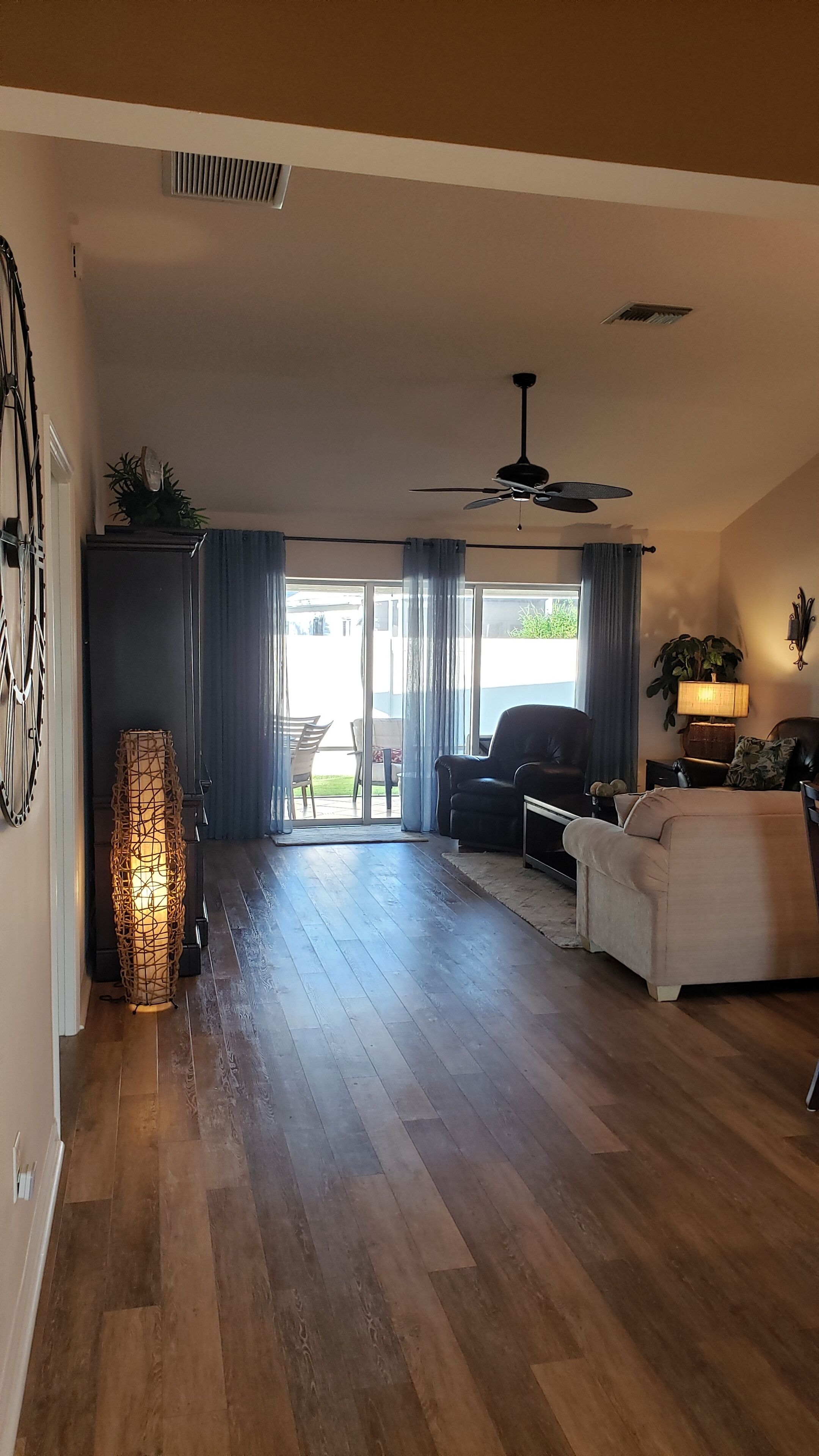 Un salon spacieux doté d’un plancher en bois, d’un ventilateur de plafond, d’un canapé, d’une table basse et d’un coin repas avec des chaises.