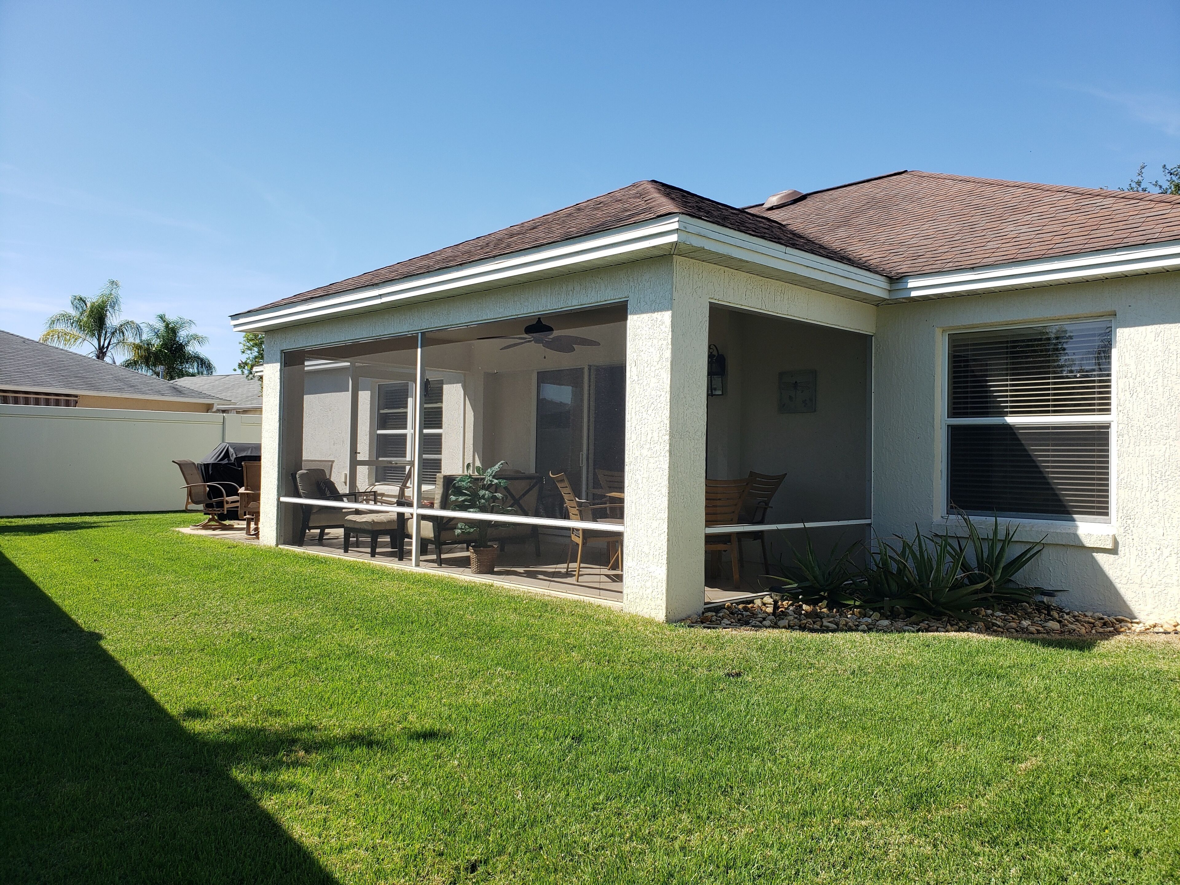Une maison avec un patio couvert, une pelouse et un garage.