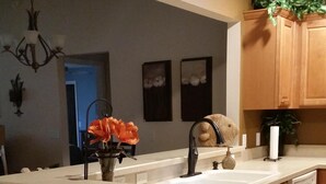 A modern kitchen with a large island, wooden cabinets, and a built-in dishwasher. - Walk to Lake Sumter Landing! Golf cart included! (The Villages)