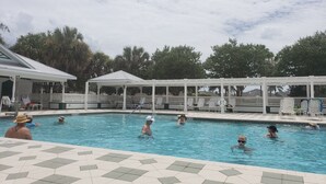A swimming pool with multiple lanes, surrounded by white lounge chairs and a covered pavilion. - Walk to Lake Sumter Landing! Golf cart included! (The Villages)