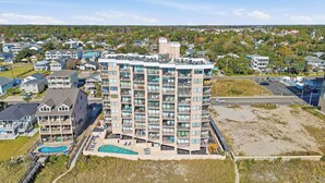 Un hôtel de grande hauteur doté de nombreux balcons, d’une piscine et d’un parking.