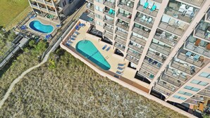 Un hôtel de grande hauteur doté de nombreux balcons, d’une piscine et d’une terrasse ensoleillée.