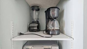 A kitchenette with a Hamilton Beach blender and a Rival coffee maker on a white shelf, and a microwave below.