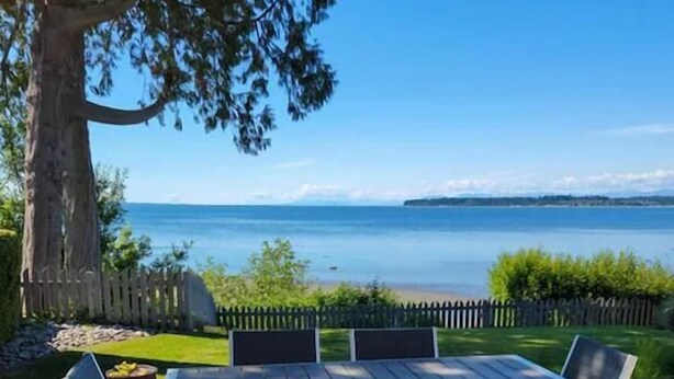 An outdoor patio with a table and chairs, a tree, and a view of a body of water. - On the beach!! Oceanfront luxury - Incredible Views and Private Beach Access (Blaine)