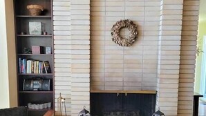A living room with a fireplace, a bookshelf, and a wicker chair. - On the beach!! Oceanfront luxury - Incredible Views and Private Beach Access (Blaine)