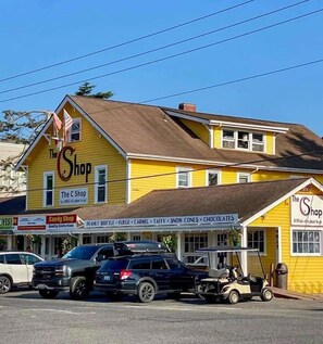Un bâtiment jaune avec une enseigne indiquant « The Shop » et, en dessous, une autre enseigne pour une confiserie.