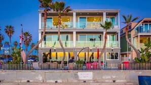 Un hotel de varios pisos con vistas a la playa, con balcones y un primer plano de arena.