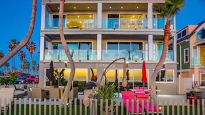 Un hotel de varios pisos con mesas al aire libre y palmeras.