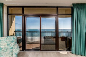 En balkon med udsigt over havet, en skydedør og en sofa med et mønster.