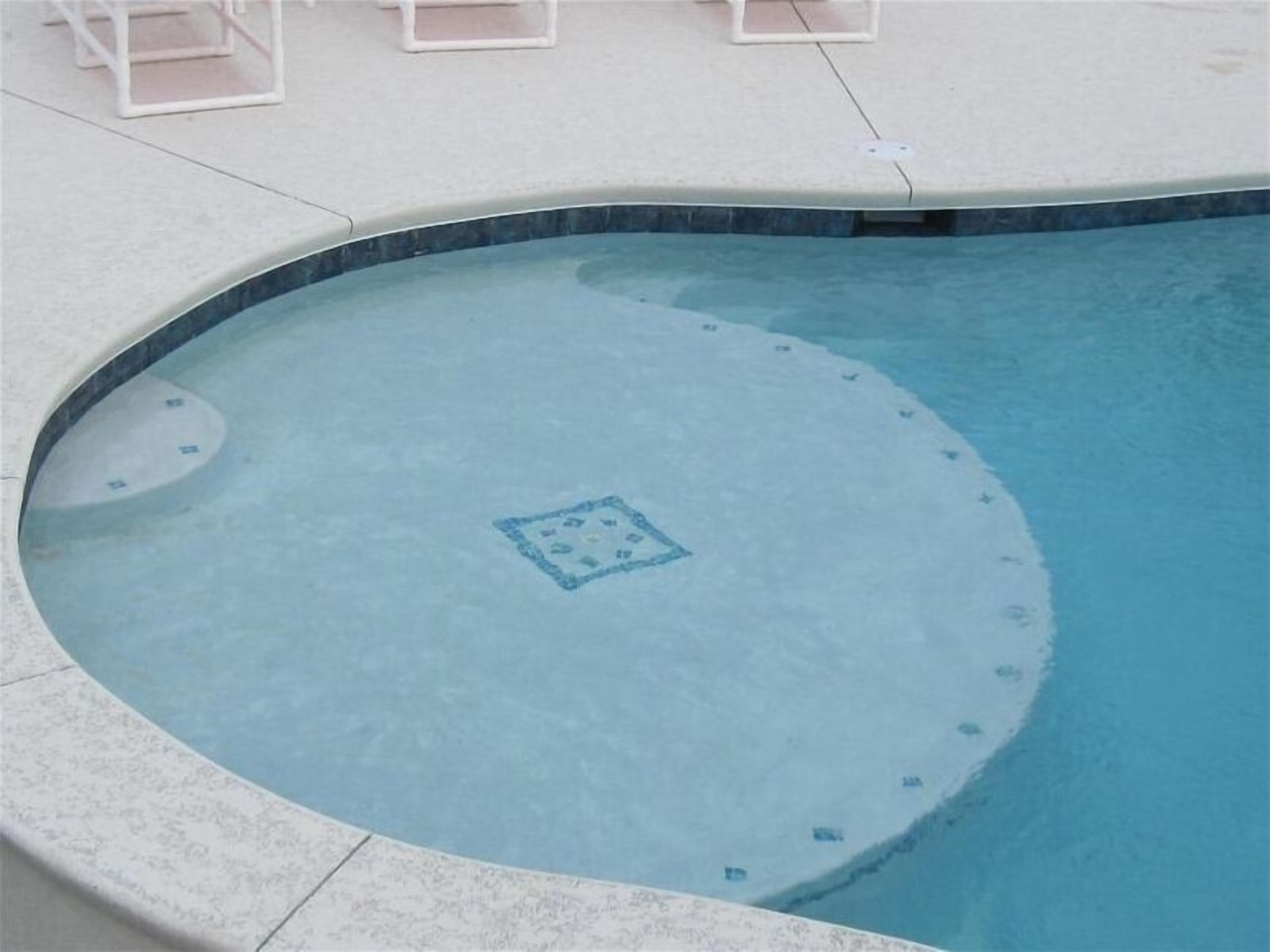 Una piscina circular con borde de azulejos y un diseño decorativo en el centro.